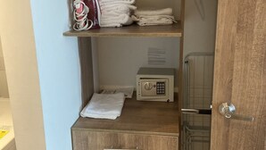 A wooden wardrobe with a lockable safe, a hanging iron, and neatly folded towels. - Charming 1-bedroom apartment in Barranquilla (Barranquilla)