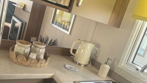 A kitchen with a stainless steel range hood, a kettle, and a sink. - 2-bed Cabin, Sleeps 4 in Cayton Bay (Scarborough)
