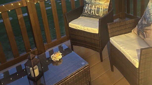 A covered patio with wicker furniture, a glass table, and a string of lights. - 2-bed Cabin, Sleeps 4 in Cayton Bay (Scarborough)