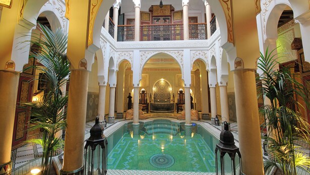 An indoor swimming pool with ornate arches and columns, surrounded by lush greenery. - Luxurious Authentic Riad in the heart of the Medina (Morocco)