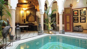 An indoor swimming pool with ornate arches and a fountain. - Luxurious Authentic Riad in the heart of the Medina (Morocco)