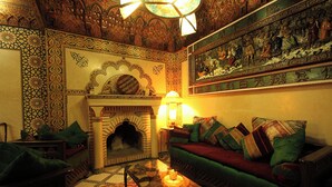A traditional interior with a sofa, a fireplace, and intricate wall designs. - Luxurious Authentic Riad in the heart of the Medina (Morocco)