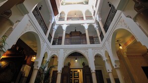 A multi-level interior with ornate arches and columns, a central open space, and a balcony with decorative railings. - Luxurious Authentic Riad in the heart of the Medina (Morocco)
