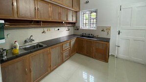 A kitchen with wooden cabinets, a stainless steel sink, a gas stove, and a window with bars.