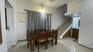 A dining area with a table and chairs, a staircase, and a bathroom with a mirror.