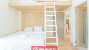 A modern bedroom with a bunk bed, a ladder, and a neatly made bed.