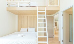 A modern bedroom with a bunk bed, a ladder, and a neatly made bed.