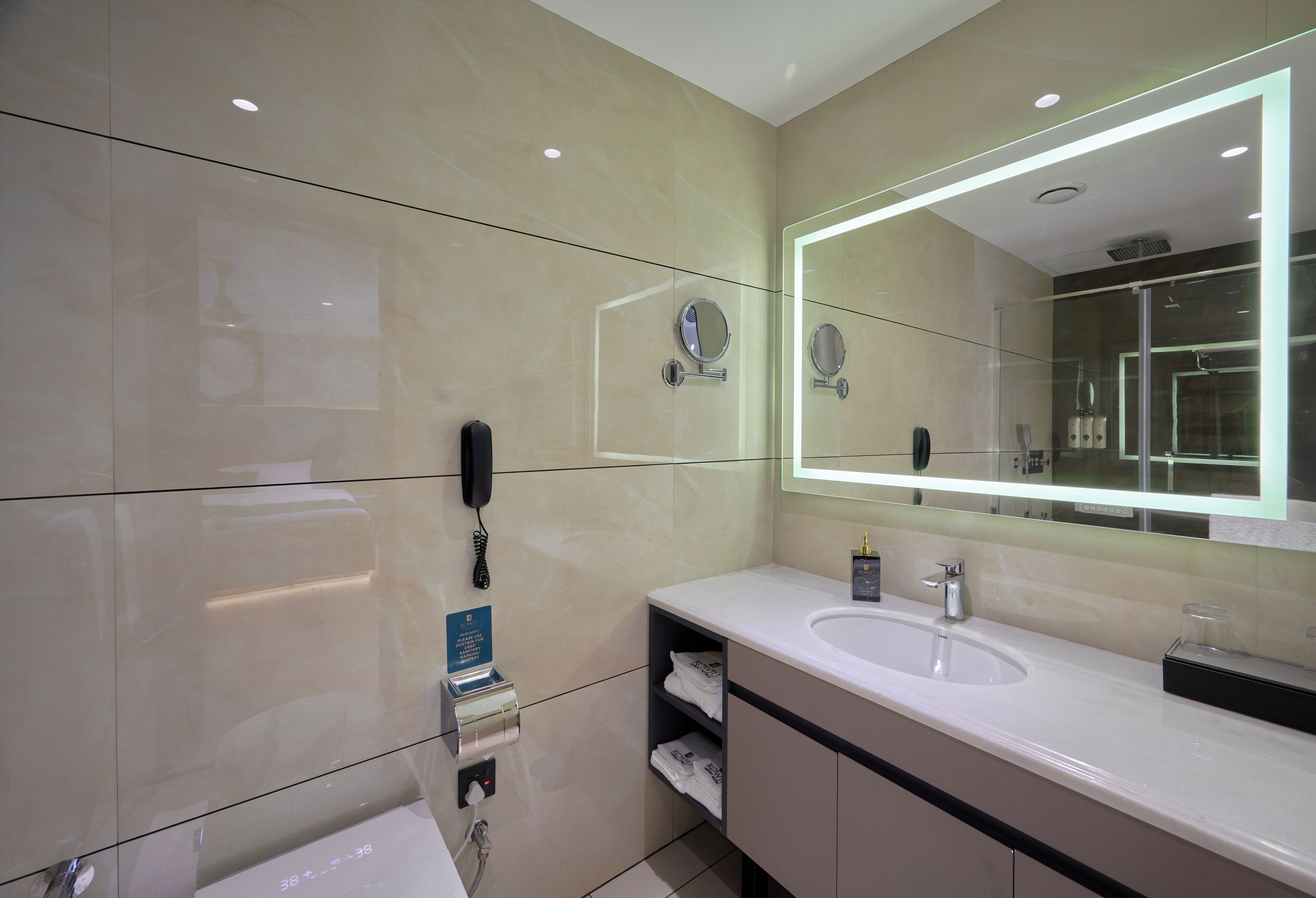 A modern bathroom with a large mirror, a sink, and a glass shower enclosure.