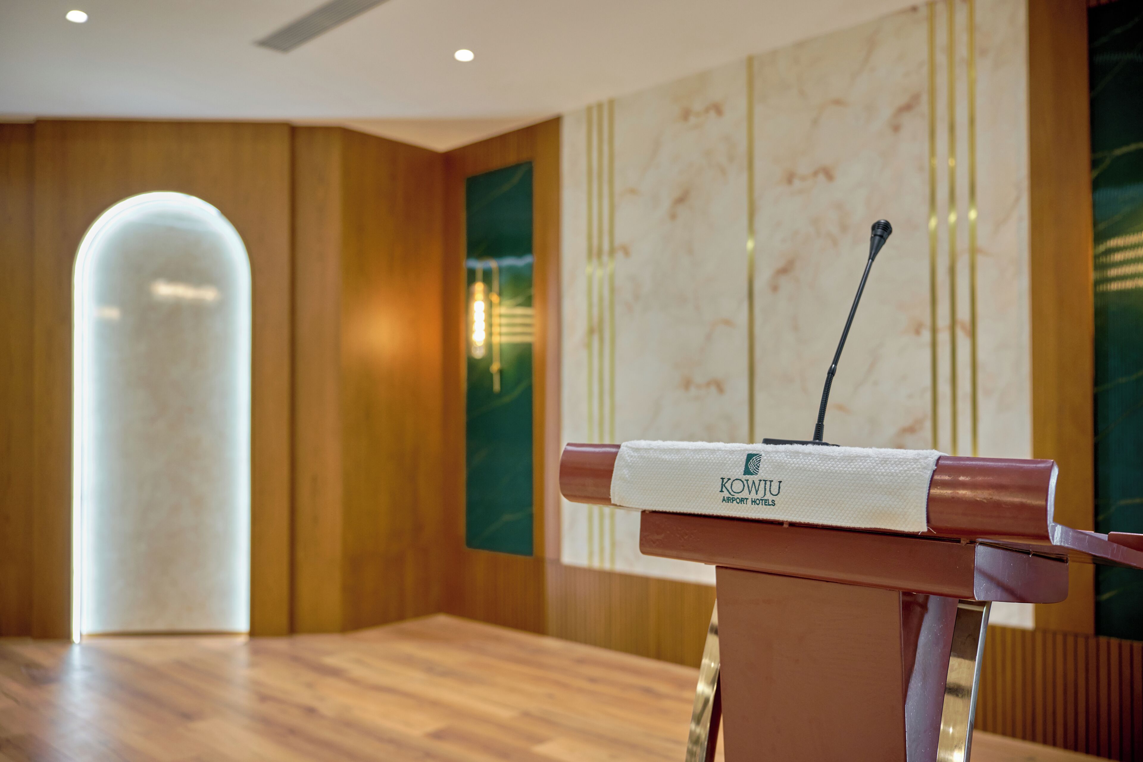 A podium with a microphone and a towel, a wooden floor, and a marble wall with vertical lines.