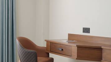 A modern office space with a wooden desk, a cushioned chair, and a power outlet on the wall.