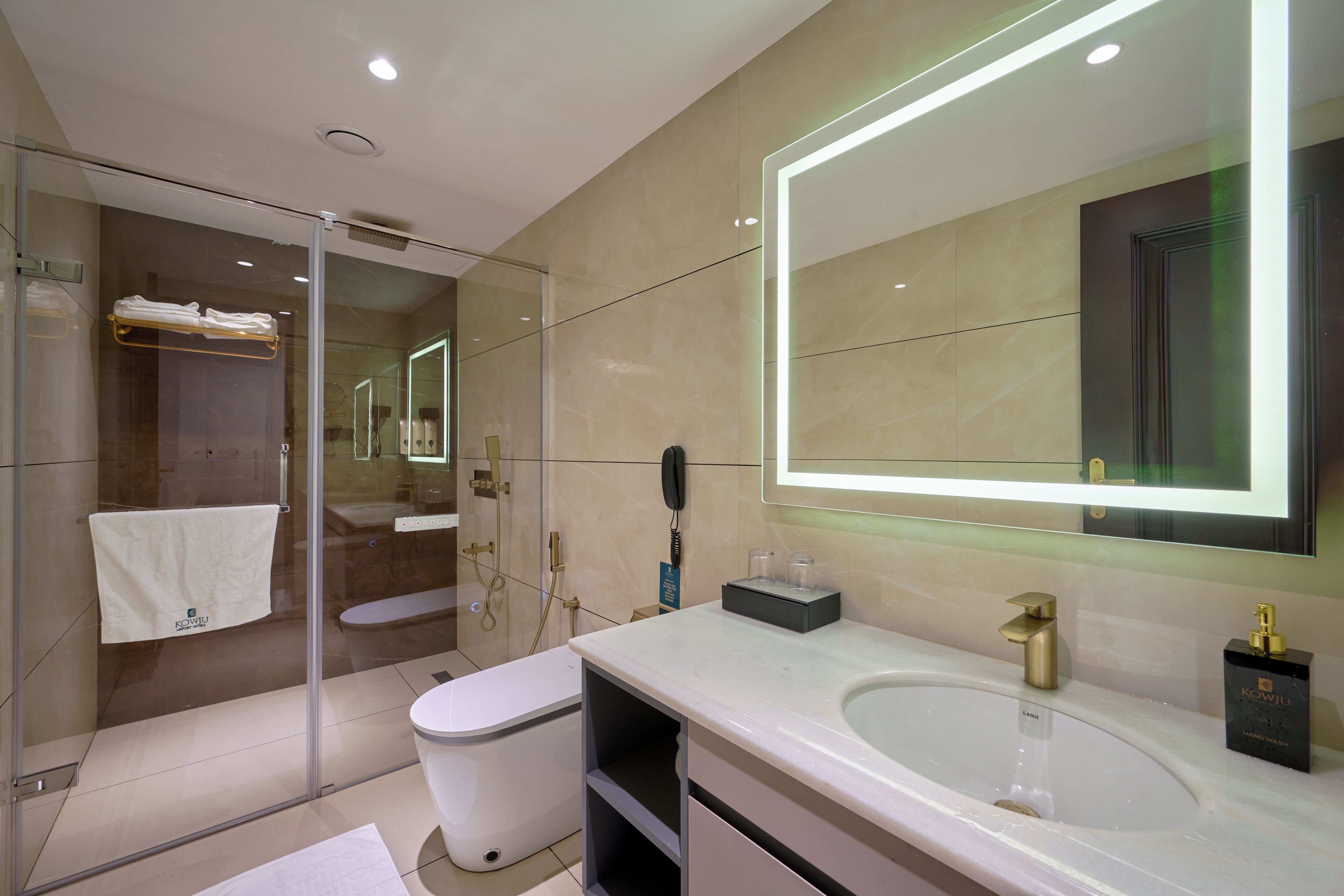 A modern bathroom with a glass shower enclosure, a white sink, and a large mirror with LED lighting.
