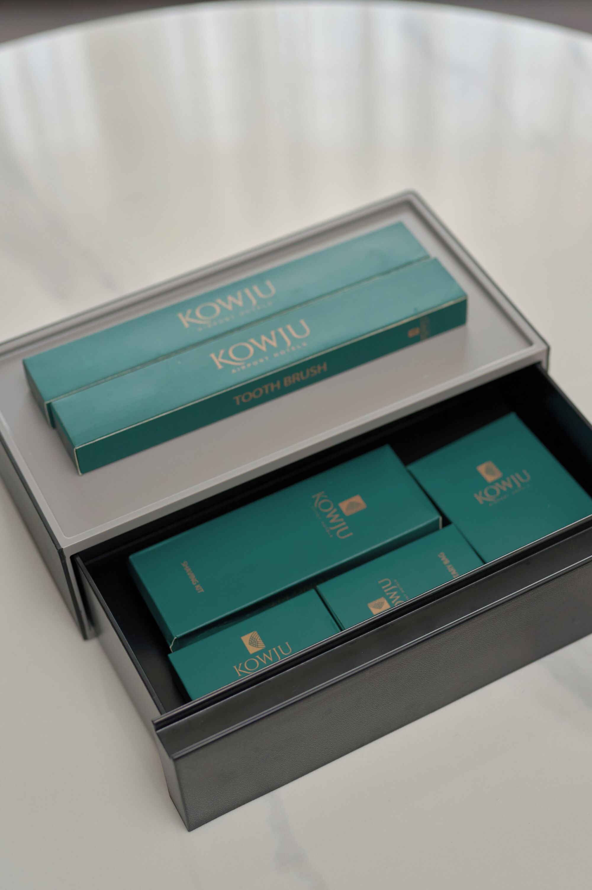 A box of KOWJU toothbrushes with a teal and black design.