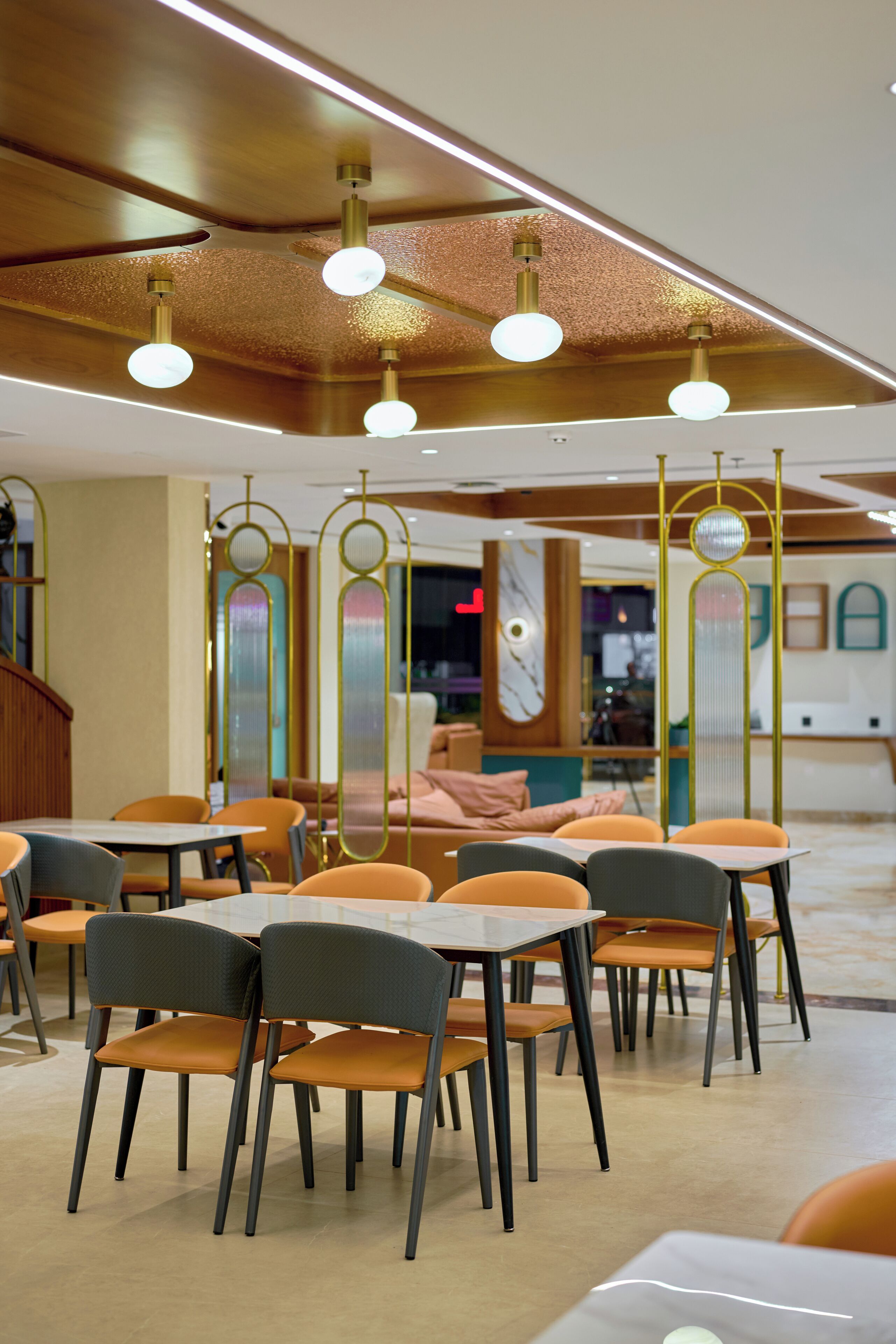 A modern dining area with tables and chairs, decorative ceiling lights, and a view of the interior.