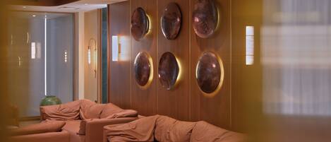 A modern lounge area with a sofa set, two small round tables, and decorative wall panels.