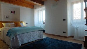 A bedroom with a bed, bedside tables, a window with curtains, and a wooden ceiling. - CasAle sul Lago di Como: serene house with beautiful view of Lake Como  (Blevio)