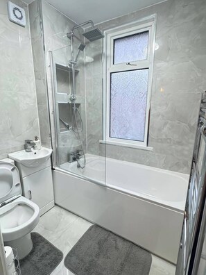 A modern bathroom with a glass-enclosed shower, a standalone sink, and a bathtub. - Charming Luton Home for Families & Business Stays (Luton)