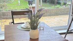 A dining table with a vase of lavender, a set of plates, and a glass. - Charming Luton Home for Families & Business Stays (Luton)