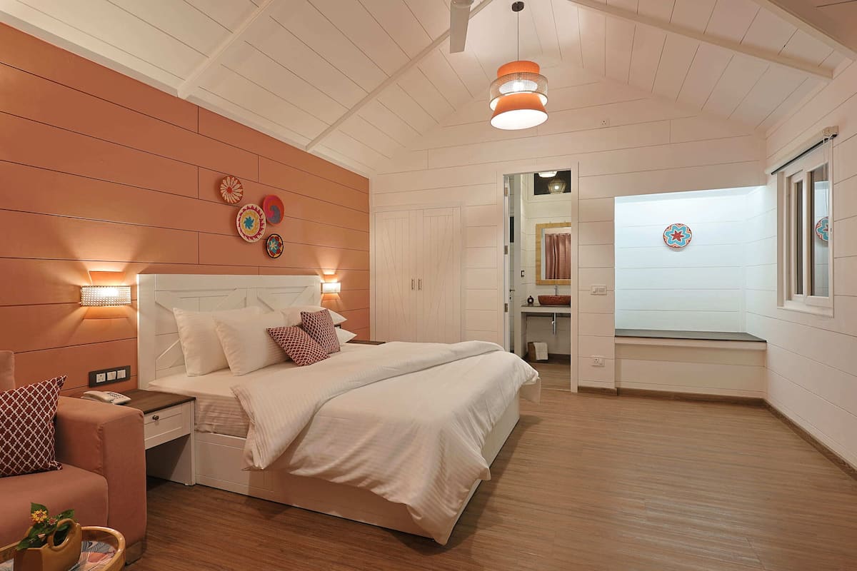A bedroom with a bed, bedside table, lamp, and a mirror.