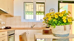 Una cocina con una mesa de madera, una planta en maceta y una ventana con un reloj.