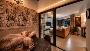 Un intérieur moderne comprenant un coin repas, un canapé et une vue sur le salon, accessible par une porte vitrée.