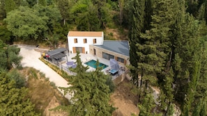 Un bâtiment à deux étages doté d’une piscine, entouré d’une forêt dense.