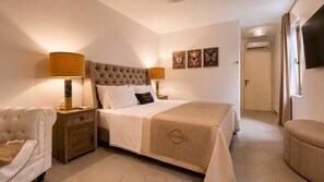 Une chambre d’hôtel avec un grand lit, deux tables de chevet avec des lampes, une chaise et un téléviseur à écran plat fixé au mur.