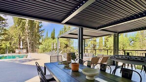 Un espace extérieur aménagé avec une terrasse, une piscine, des sièges et une table avec des chaises.