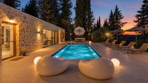 Une piscine avec des chaises longues et un mur en pierre.
