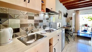 A modern kitchen with a tiled backsplash, stainless steel sink, and wooden cabinets. - Litsa Beach Maisonette (Acharavi)