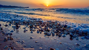 A beach with pebbles and the sun setting over the water. - Litsa Beach Maisonette (Acharavi)
