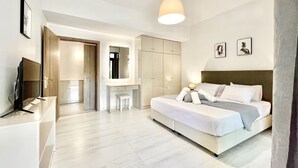 A modern hotel room with a large bed, a desk, and a wardrobe.