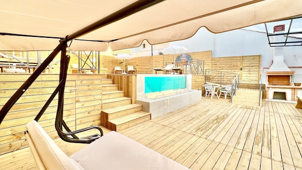 A wooden deck with a pool, outdoor seating, and a barbecue area.