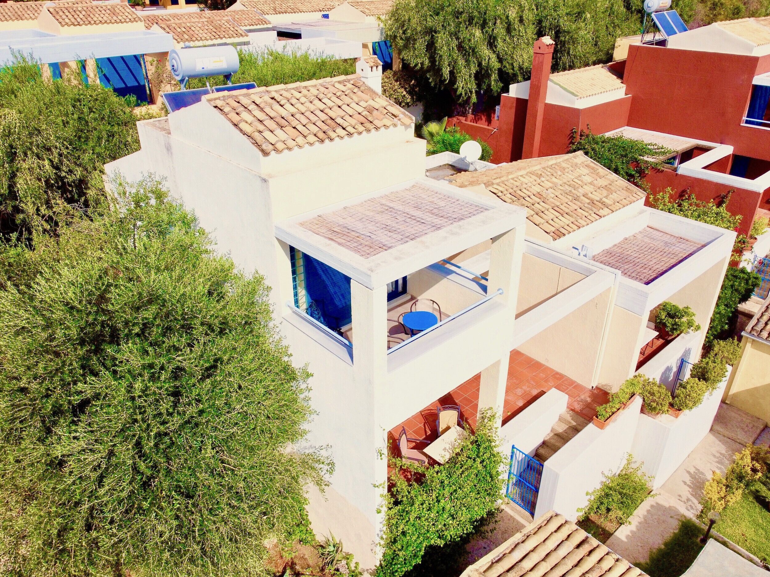 A residential building with multiple balconies, a satellite dish, and surrounding greenery.