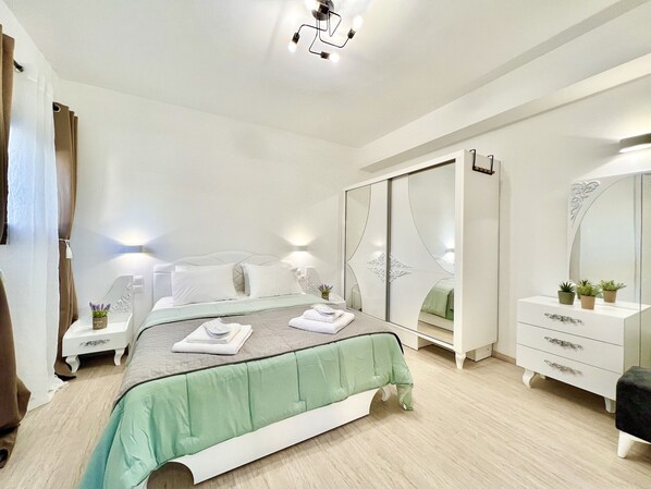Un dormitorio con cama, mesitas de noche, un armario y un espejo.