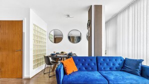 A modern living room with a blue sofa, wooden floor, and a dining area with a table and chairs. - Bullring Lux Suite- Netflix-free Parking-sleeps 6 (Birmingham)