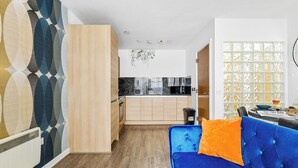 A modern kitchen with wooden cabinets, a black microwave, and a hanging light fixture. - Bullring Lux Suite- Netflix-free Parking-sleeps 6 (Birmingham)