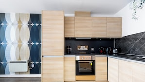 A modern kitchen with light wood cabinets, a black countertop, and a marble backsplash. - Bullring Lux Suite- Netflix-free Parking-sleeps 6 (Birmingham)