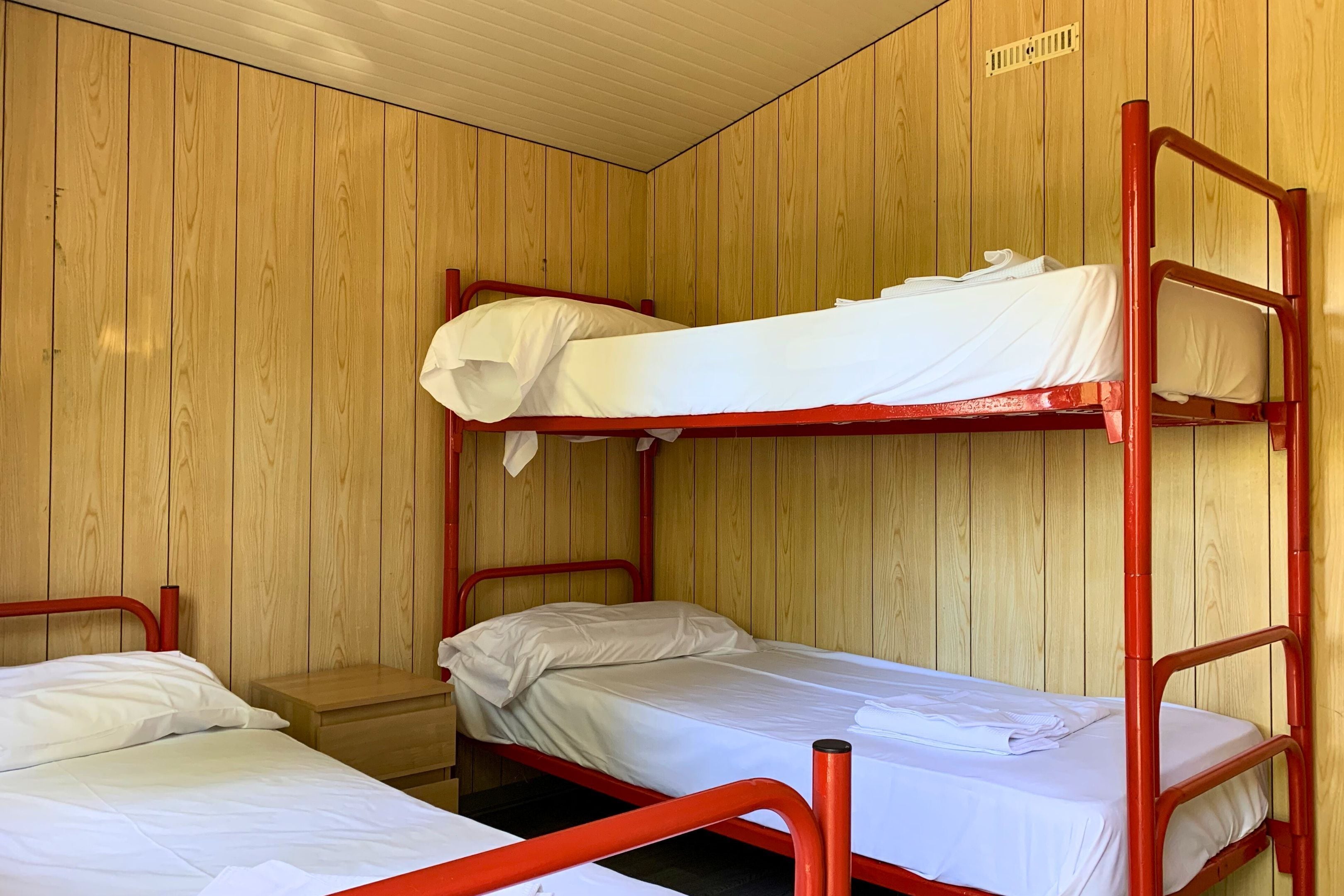 A bunk bed room with wooden walls and a small wooden nightstand.