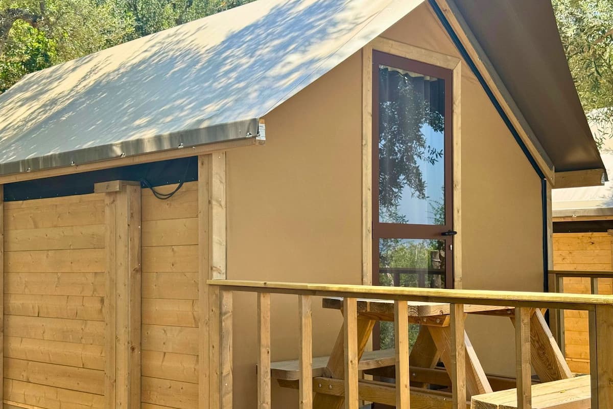 Une cabane en bois avec un toit en métal, une porte en verre et une terrasse en bois.