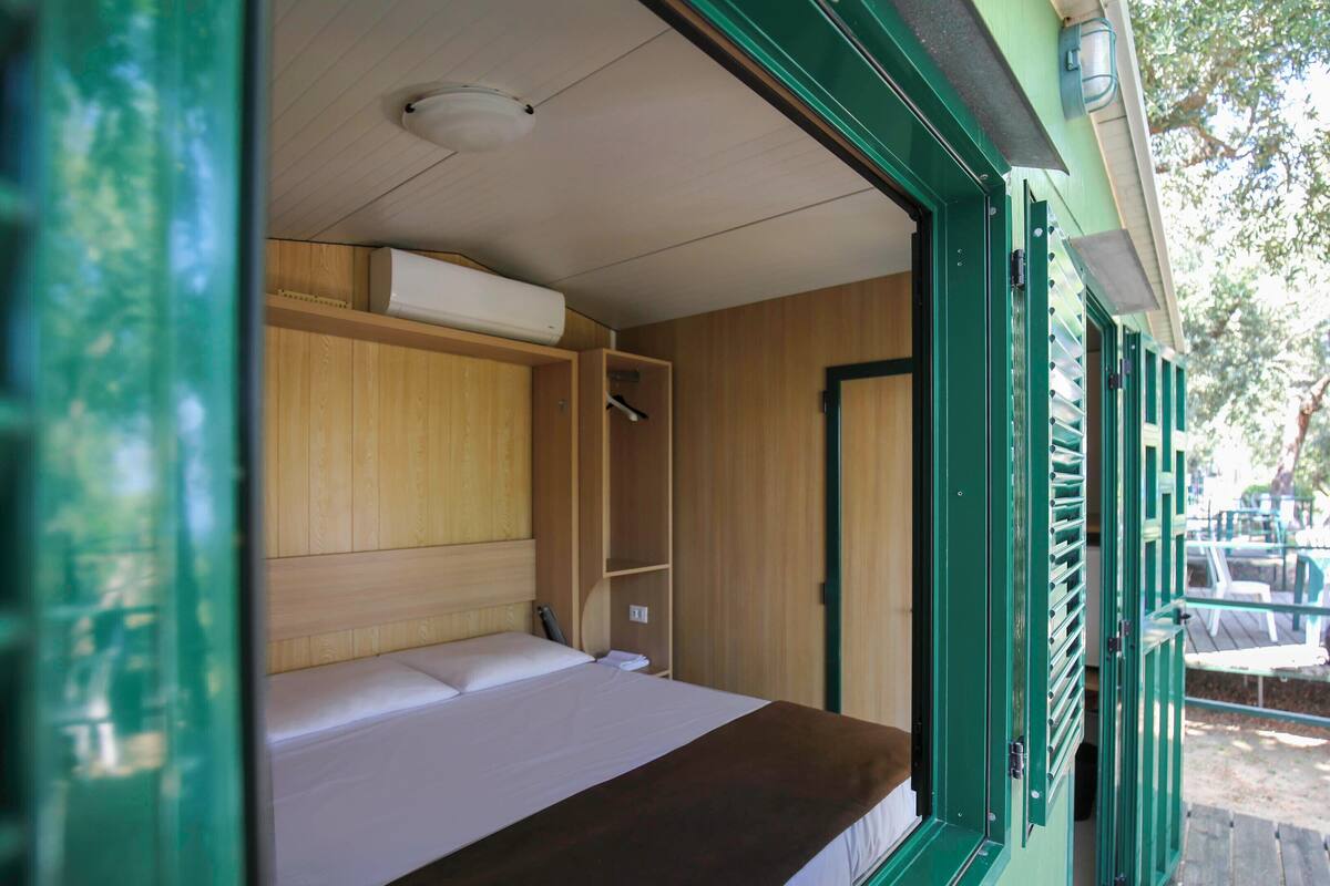 Une petite pièce comprenant un lit, une armoire en bois et un banc.