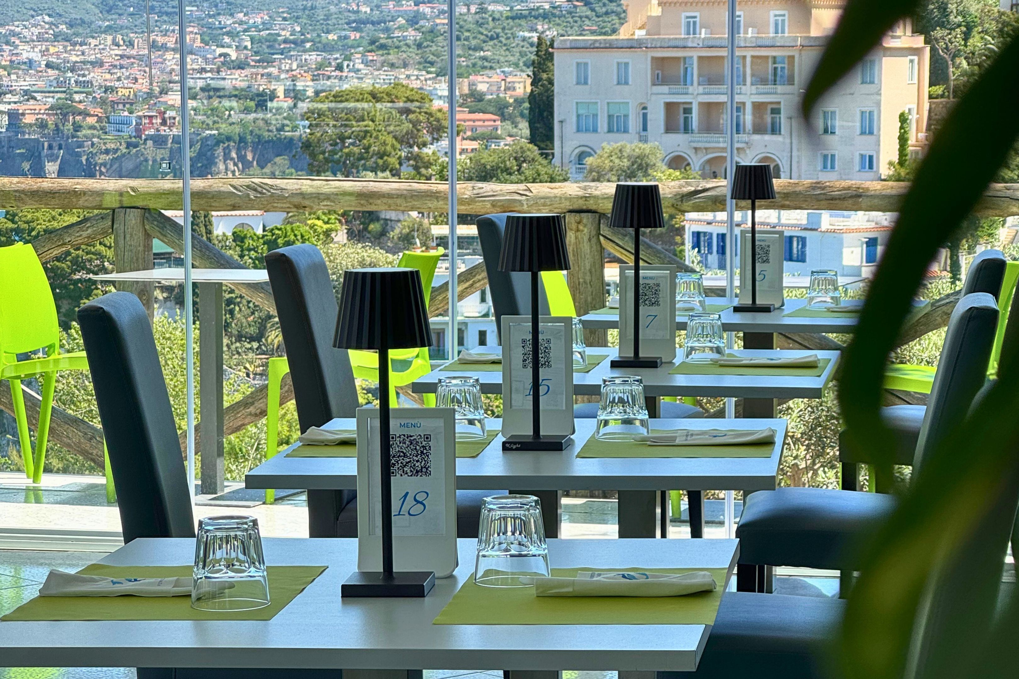 Un restaurante con terraza, mesas numeradas y vistas a la ciudad.