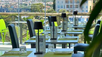 A restaurant with outdoor seating, numbered tables, and a view of the city.