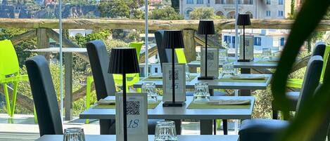 Un restaurante con terraza, mesas numeradas y vistas a la ciudad.