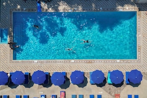 Een buitenzwembad, parasols bij het zwembad en ligstoelen