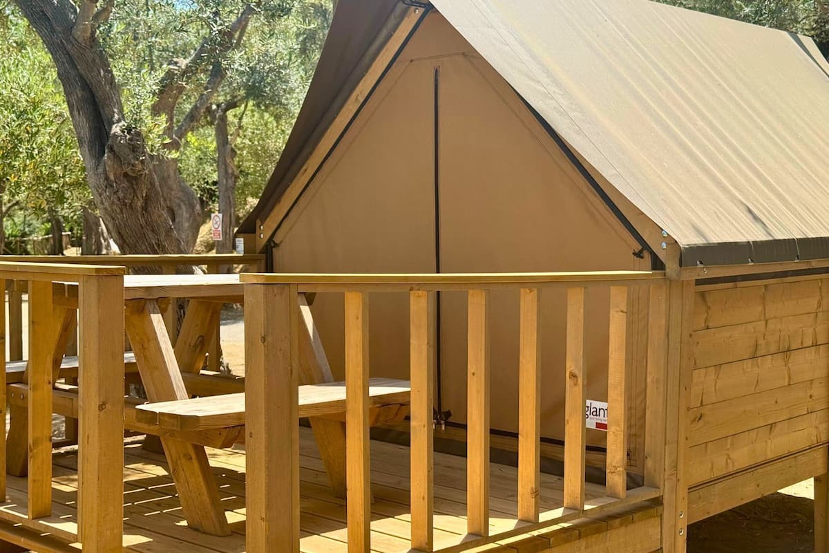 Une terrasse en bois avec une petite construction qui ressemble à un chalet, dont le toit est de couleur beige.
