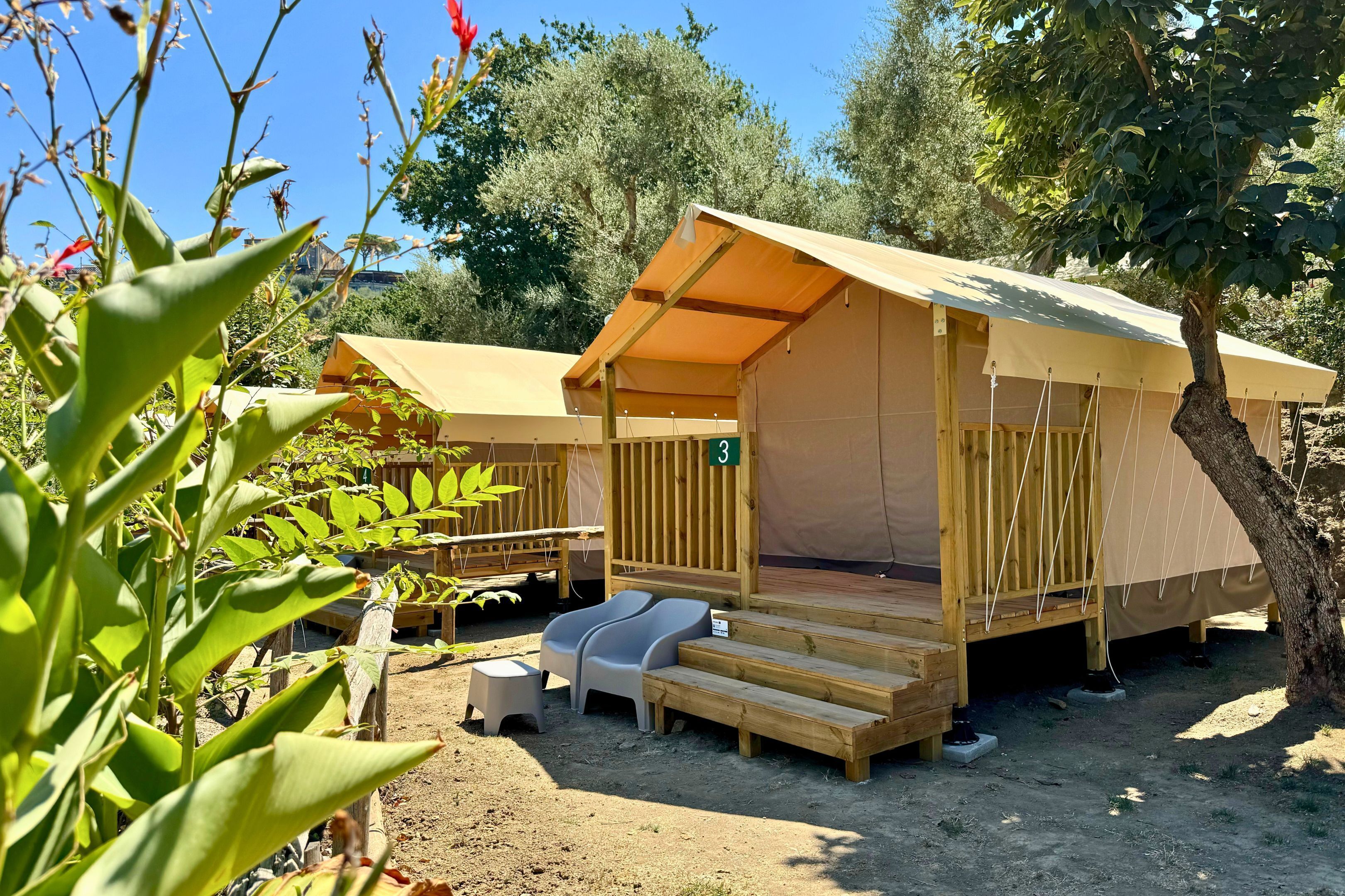Un terrain de camping avec des tentes en bois, une petite table et un banc.