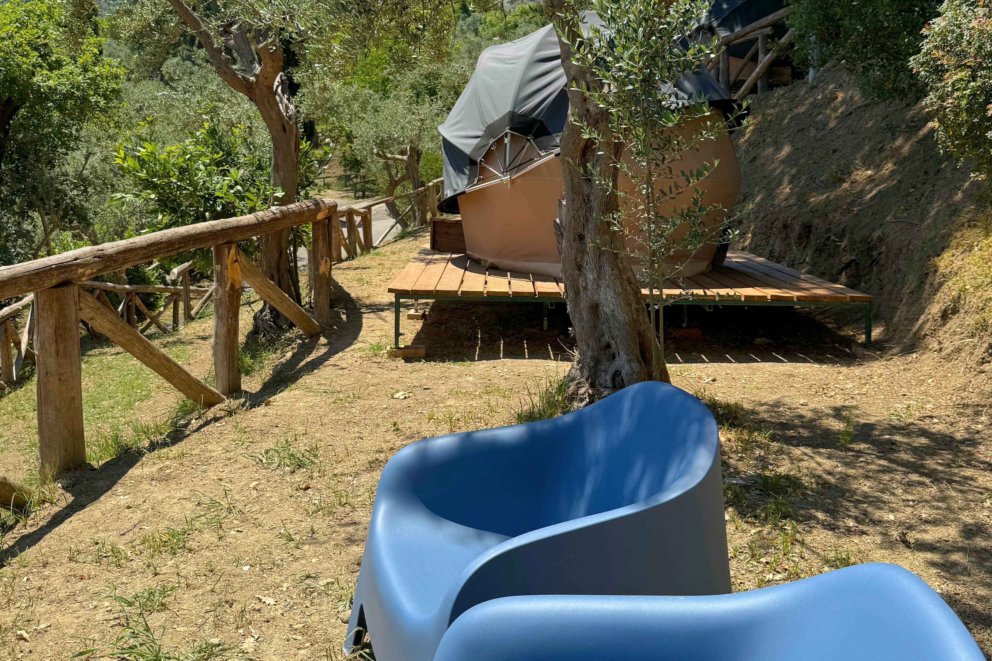 A campsite with a tent, a wooden deck, and a chair.