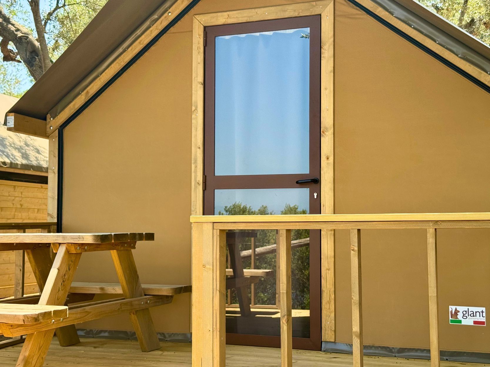 A wooden structure with a brown door and a small window, a picnic table, and a sign with the word 'glant'.