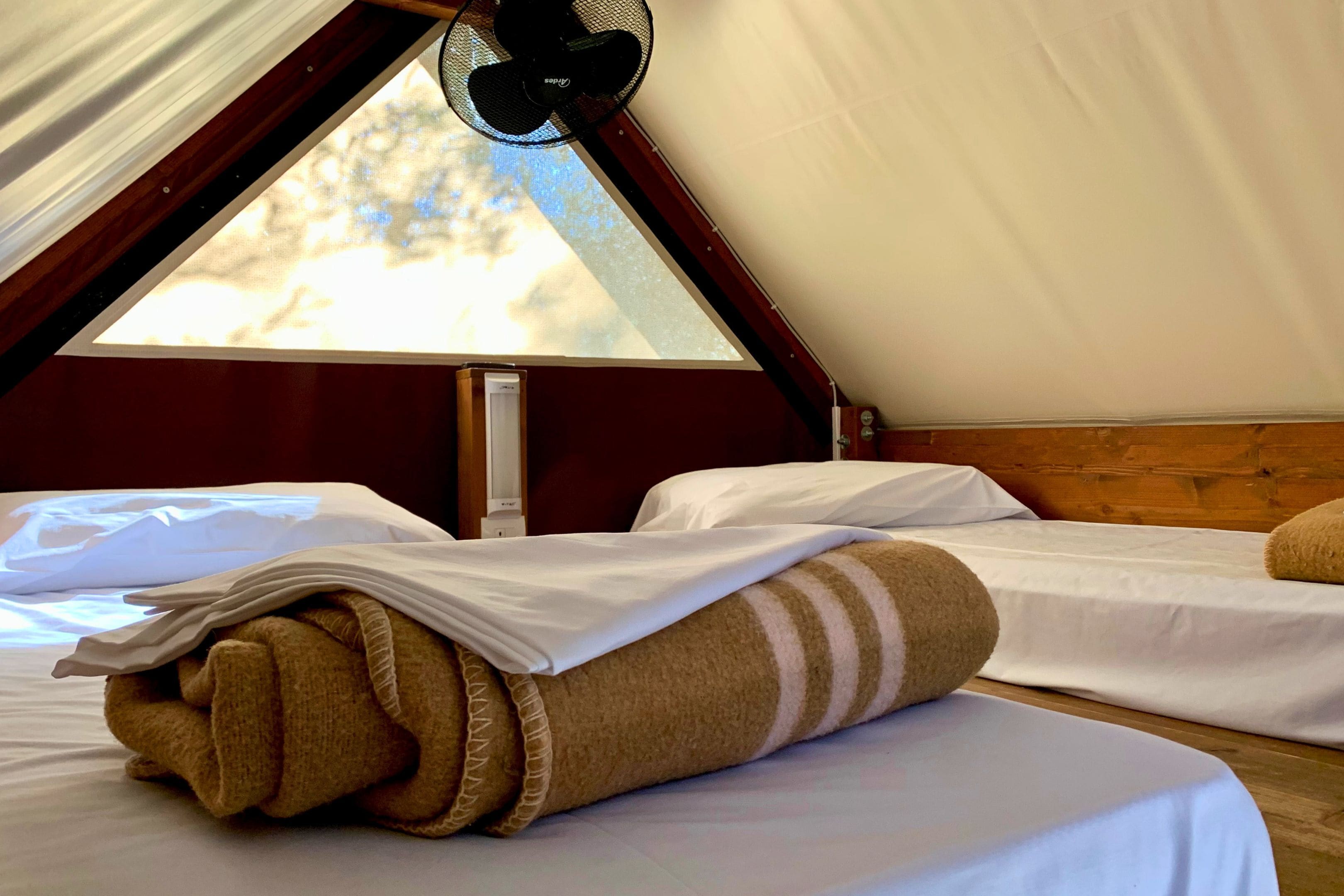Een gezellige kamer met een bed, een opgerolde handdoek en een plafondventilator.