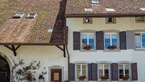 A traditional building with a tiled roof, multiple windows with shutters, and potted plants. - MyTourist (Heumen)